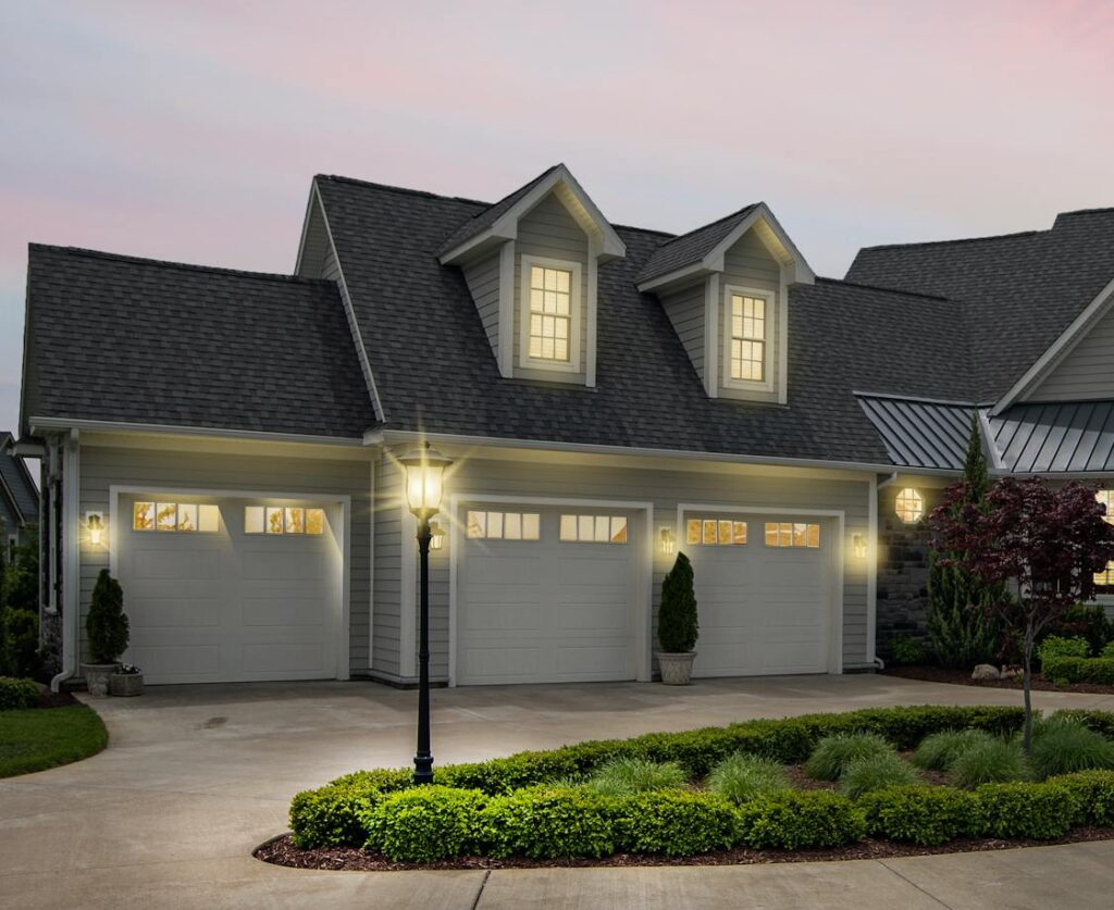 A modern suburban home at dusk, beautifully lit with exterior lights.