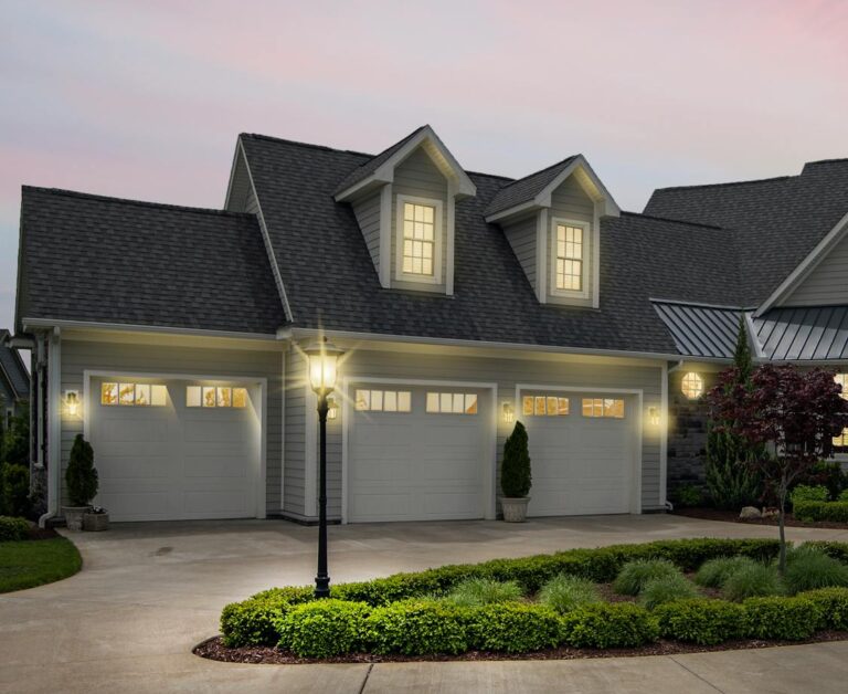 A modern suburban home at dusk, beautifully lit with exterior lights.