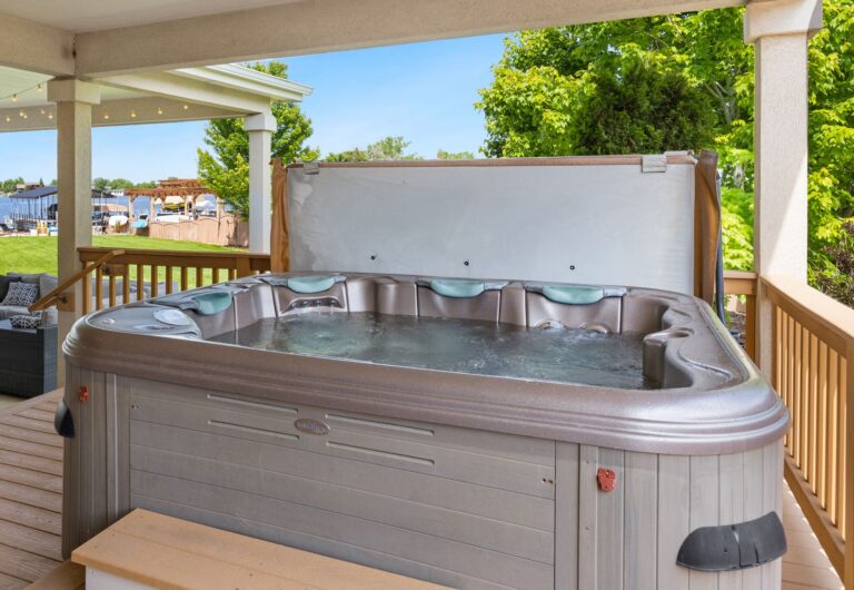Explore a serene outdoor patio featuring a luxurious hot tub overlooking a tranquil lake.